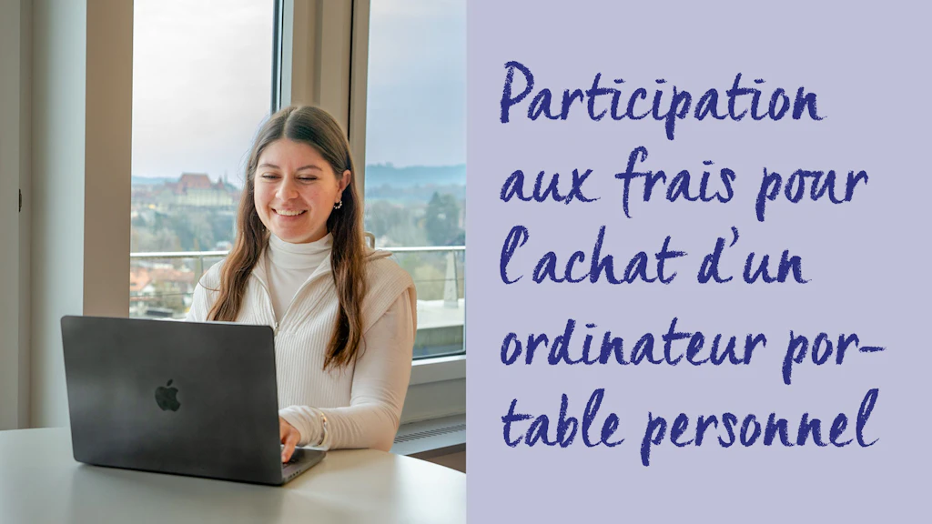 Personne assise à une table avec un ordinateur portable à logo pomme devant une fenêtre avec vue sur la ville