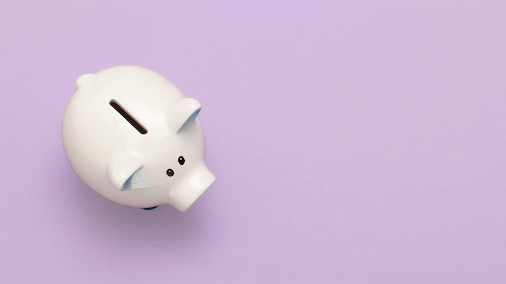 Salvadanaio bianco visto dall’alto su sfondo viola chiaro uniforme