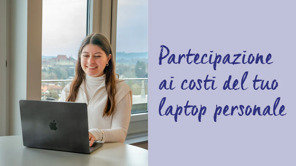 Persona seduta a un tavolo con un portatile con logo mela davanti a una finestra con vista sulla città