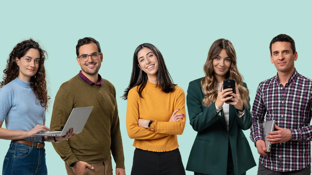 Cinque studenti in piedi fianco a fianco con abbigliamento casual e formale, uno tiene un portatile, uno uno smartphone, uno una tazza.